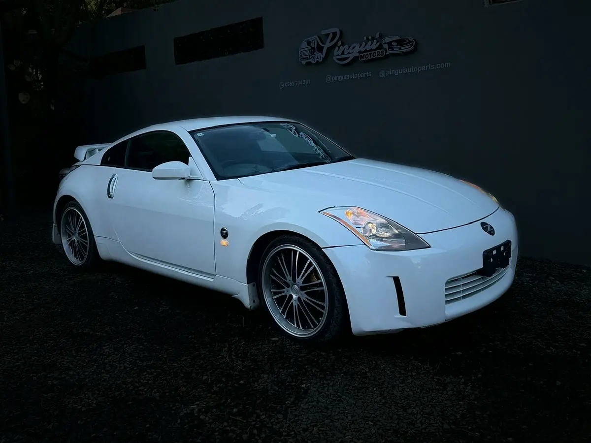 Nissan 350Z blanco frente al cartel de Pingui Motors